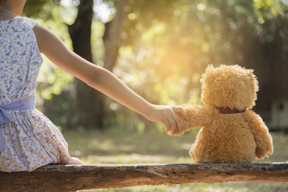 djevojčica koja ima autizam drži ruku plišanog medvjedića