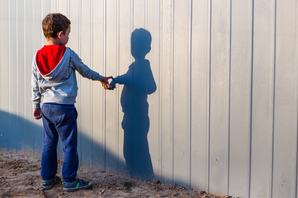 dječak koji ima autizam dodiruje vlastitu sjenu na zidu